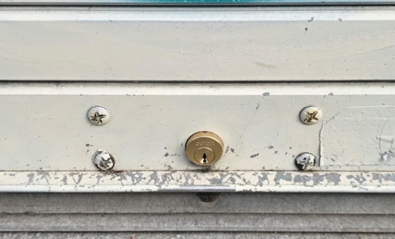 Brass lock cylinder fitted in a white metal garage door